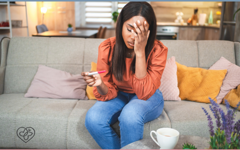 woman looking sadly away from a pregnancy test